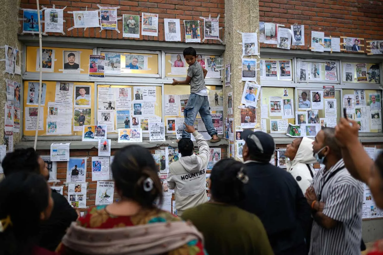 Muro con fotografías de desaparecidos por deslave en Nepal.