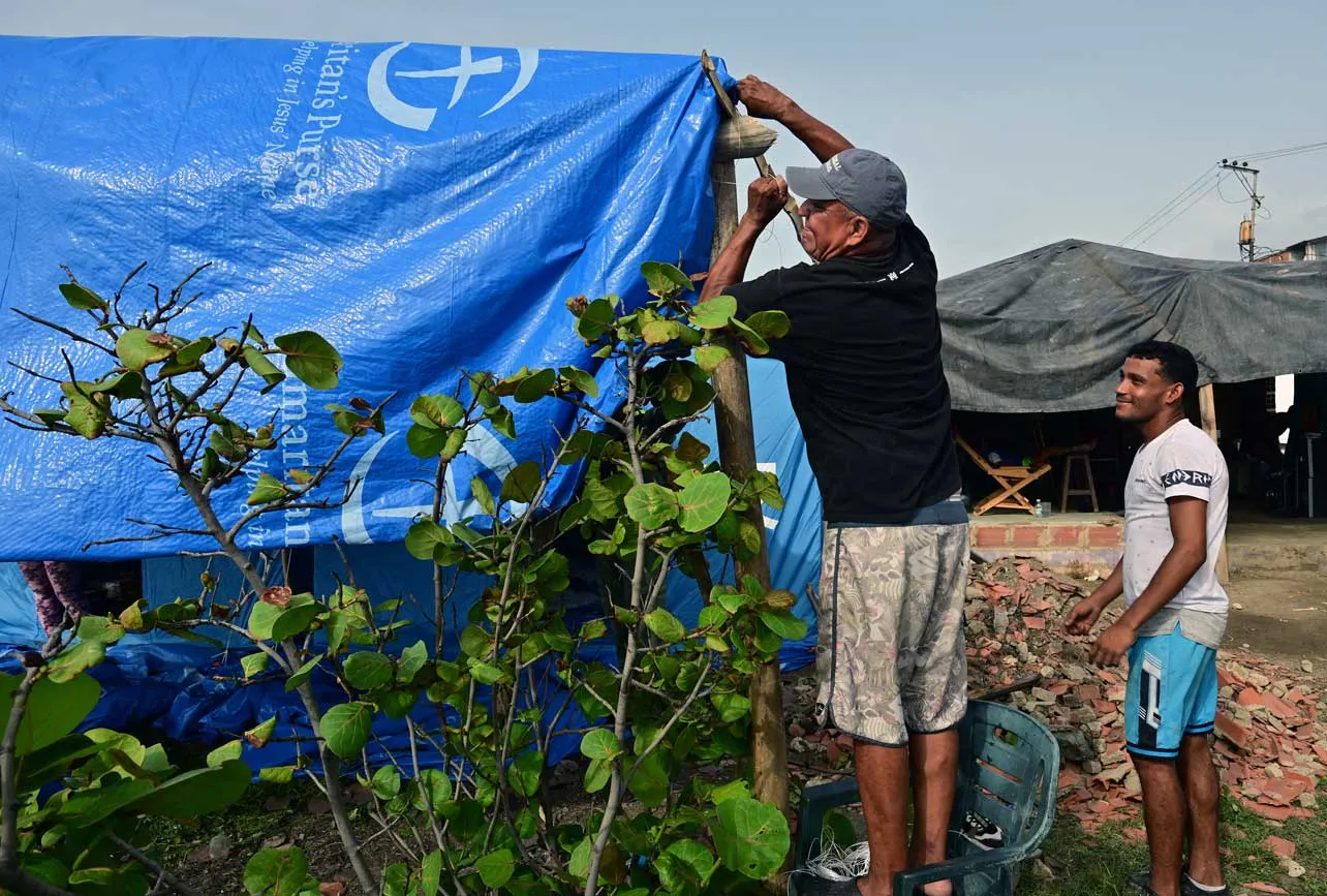 Dos personas levantan una carpa.