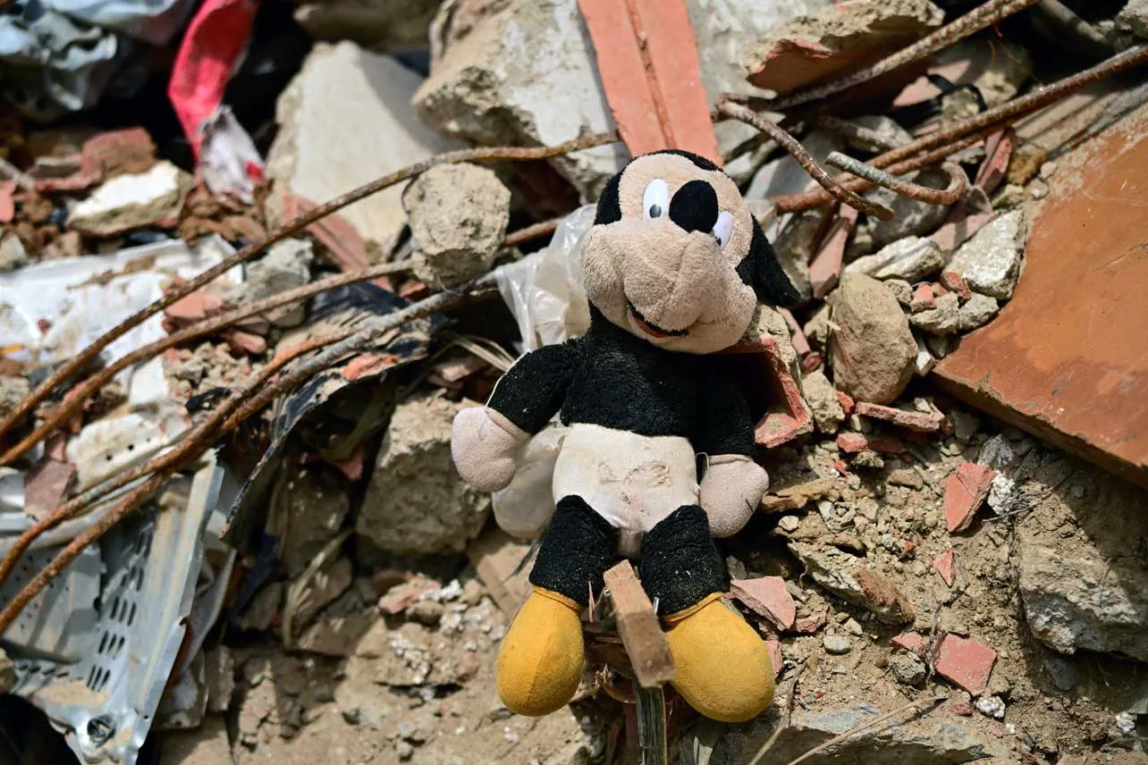 Un peluche de Mickey Mouse entre escombros.