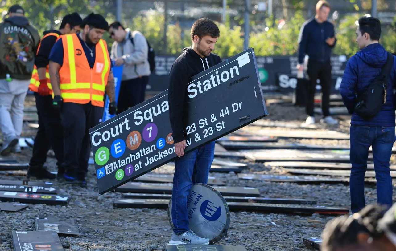 Una persona carga con una señal antigua del metro de Nueva York.