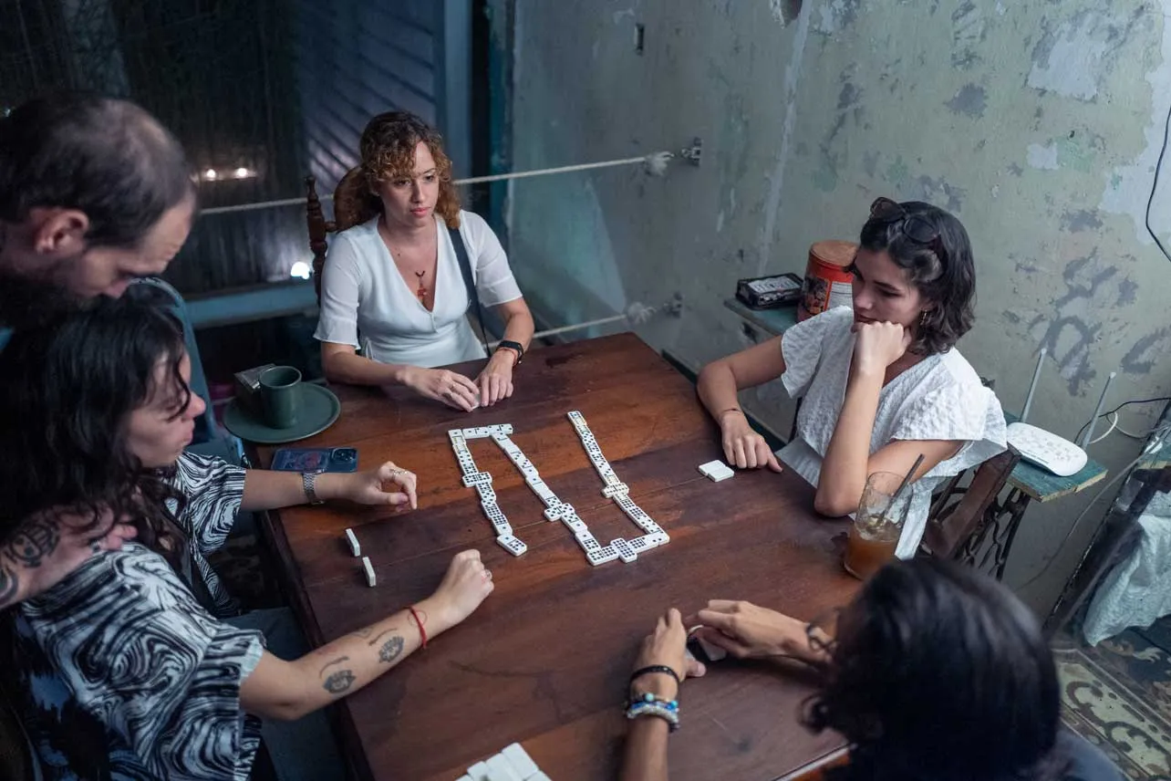 Jóvenes sentadas alrededor de una mesa jugando dominó.