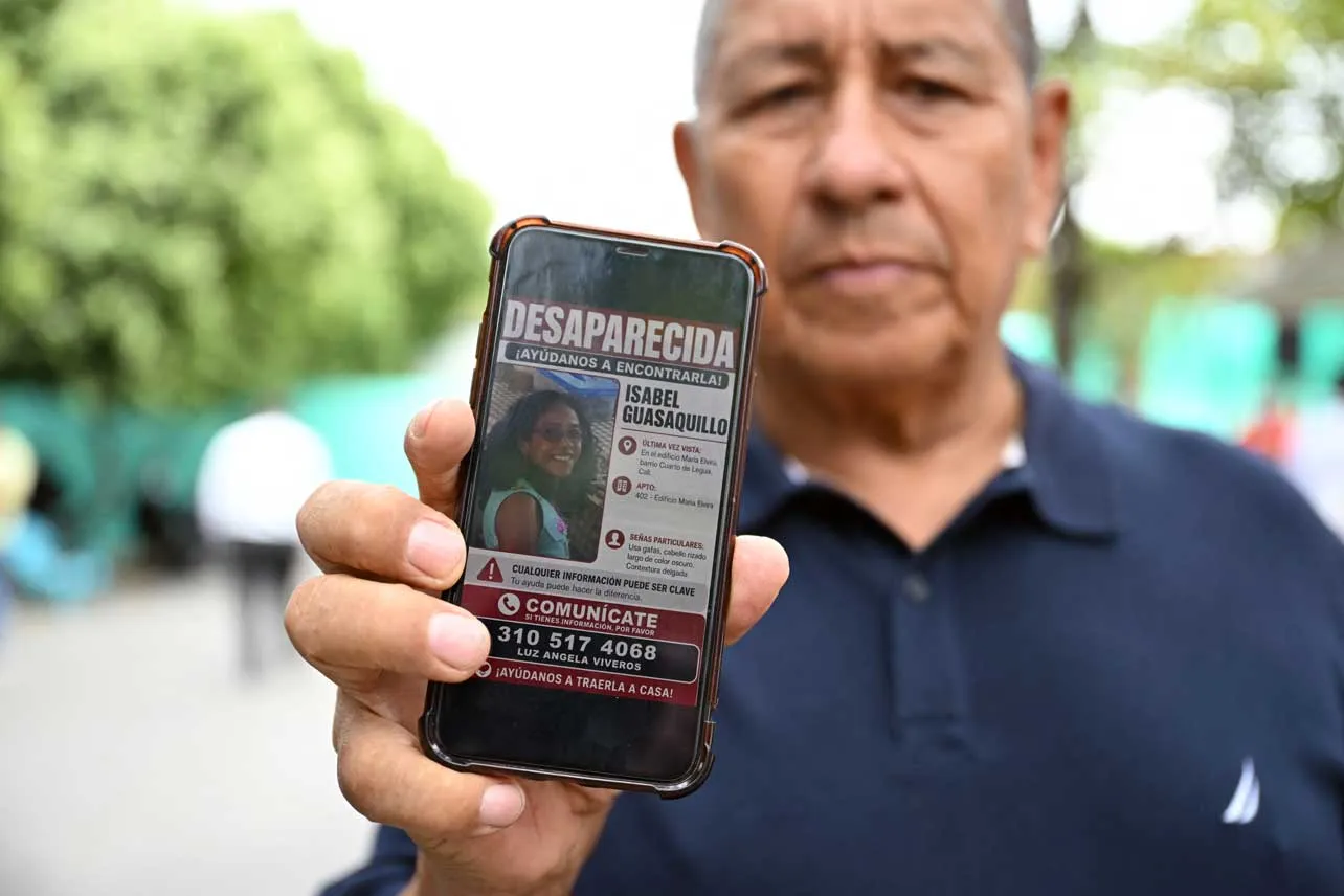 Un hombre muestra en su teléfono el aviso de desaparecida de su familiar.