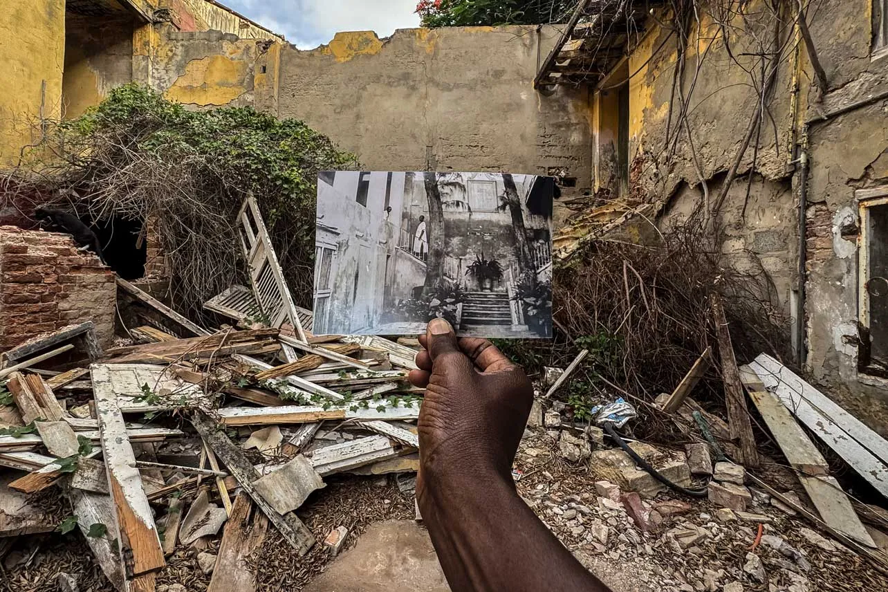 Una persona sostiene una foto frente a las ruinas de un edificio en Sait-Louis en Senegal.