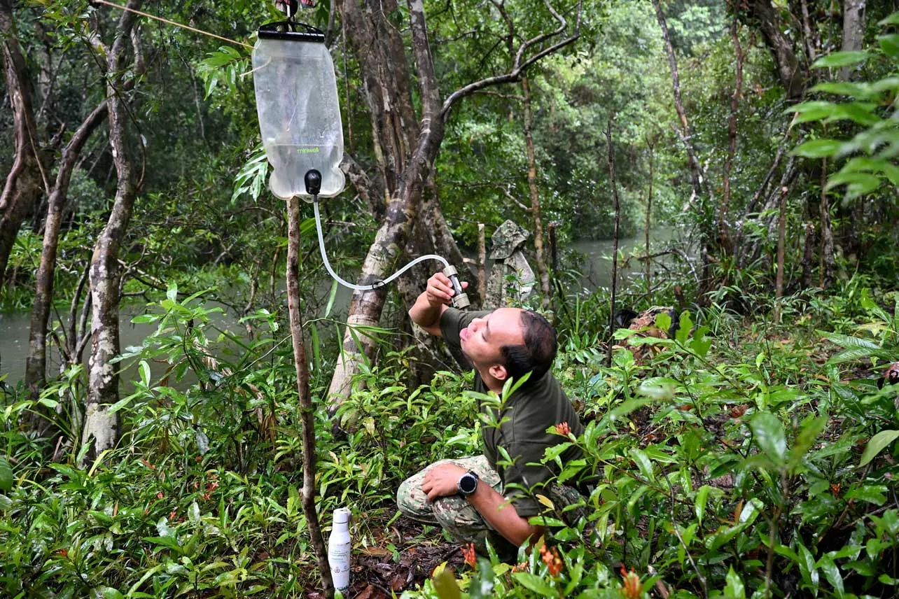 Ambientalista tomando agua en bosque de Camboya.